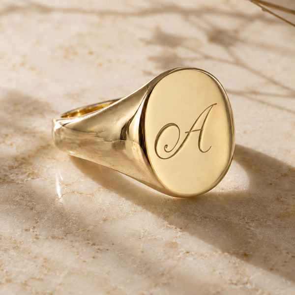 Star Jewellers Oval Shape Signet Ring with a plain polished gold face on textured stone