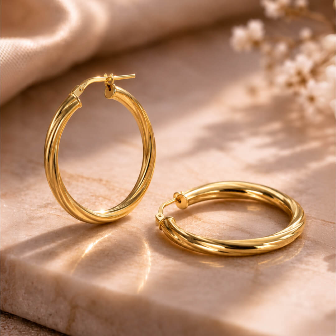 Star Jewellers Twisted Hoop Earrings in 14ct gold plating displayed on a stone surface